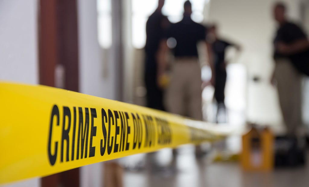 crime scene tape in building with blurred forensic team background